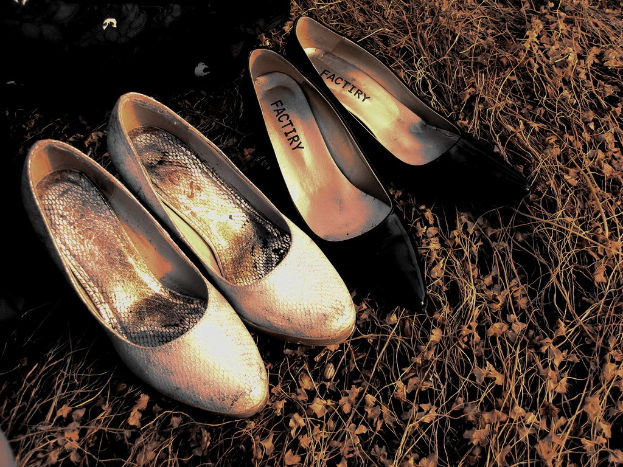 Zwei Paare Ballettschuhe, ein Paar rosa und ein Paar schwarz, sind nebeneinander auf einem Holzfußboden platziert.