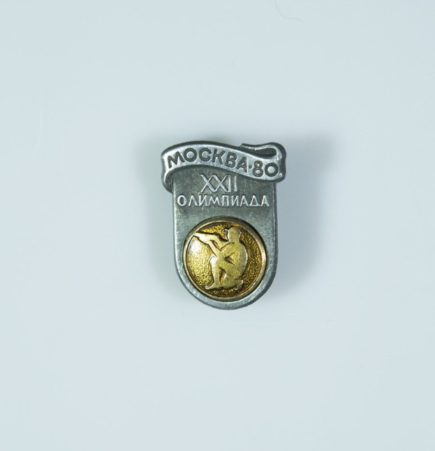 Silber- und goldener Anstecker mit einem Porträt eines Mannes, der das 80-jährige Jubiläum der Olympischen Spiele in Moskau feiert, mit Text.