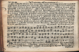 Ein aufgeschlagenes Buch mit musikalischen Noten auf den Seiten vor einem dunklen Hintergrund, mit dem Text 'bibl münchen' auf der Seite sichtbar.