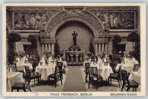 Ein altes Schwarz-Weiß-Foto eines Berliner Restaurants mit Tischen, Stühlen, Blumenvasen, einer Statue, Skulpturen, Pflanzen und Text am unteren Rand.