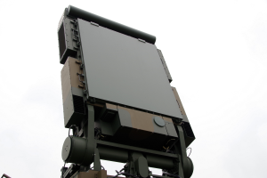 Ein militärisches Fahrzeug mit einem Radar auf dem Dach, vor einem klaren blauen Himmel.