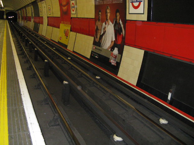 Eine Bahnschiene mit Plakaten an der Wand neben ihr.