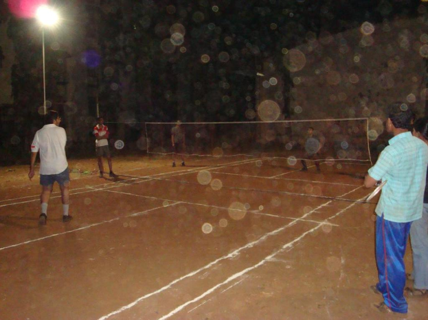 Eine Straßenlaterne an der linken Ecke mit ein paar Männern, die Volleyball auf dem Boden spielen.