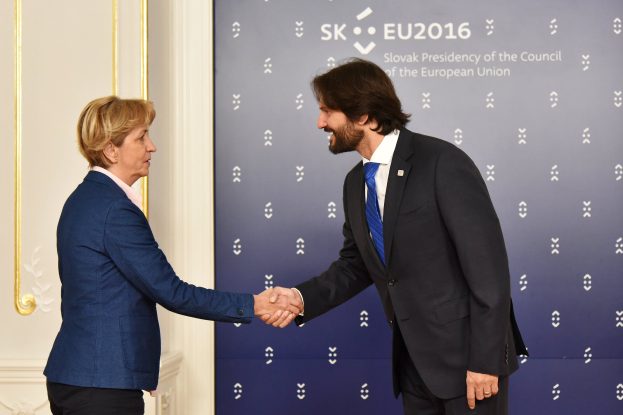 Bundeskanzlerin Angela Merkel und Bundespr├Ąsident Joachim Gauck, die sich vor einer Wand mit einem Banner "EU-Gipfel" und einer Tür im Hintergrund die H├Ąnde schütteln und beide l├Ącheln.