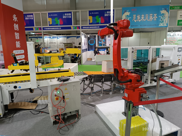 Eine Gruppe von Robotern auf einem Tisch in einer Fabrikumgebung umgeben von Maschinen, Kabeln, Leiterplatten, Beleuchtung und Menschen im Hintergrund.