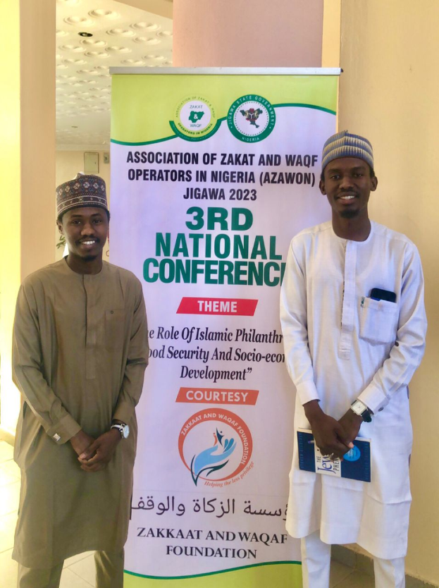 Zwei Männer vor einem Banner mit der Aufschrift "3. Nationaler Kongress" mit einer Säule und Deckenbeleuchtung im Hintergrund, wahrscheinlich an der 2023er-Veranstaltung teilnehmend.
