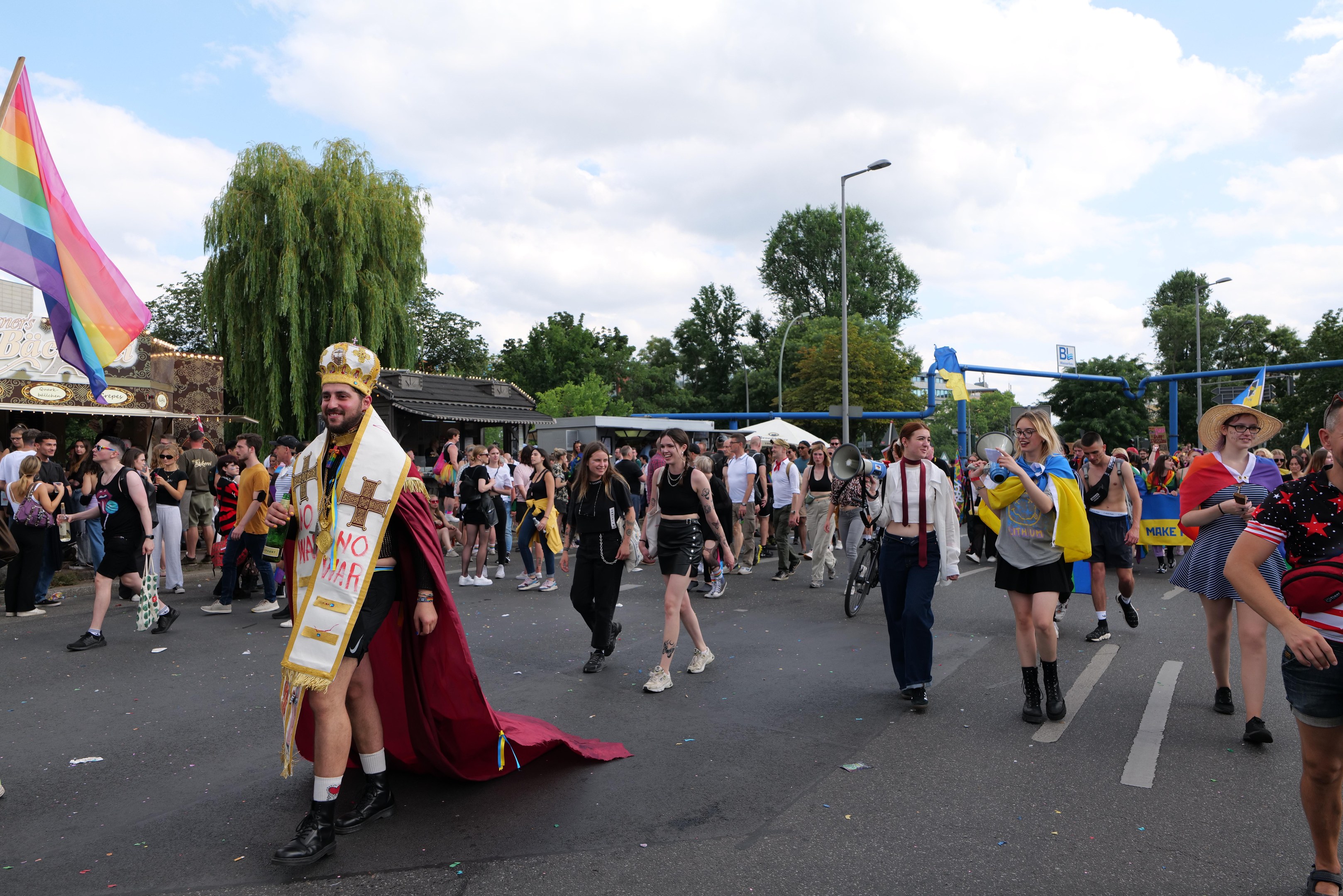 Eine Gruppe von Menschen bei der Christopher Street Day Parade 2018 mit einer Regenbogenflagge und Musikinstrumenten.