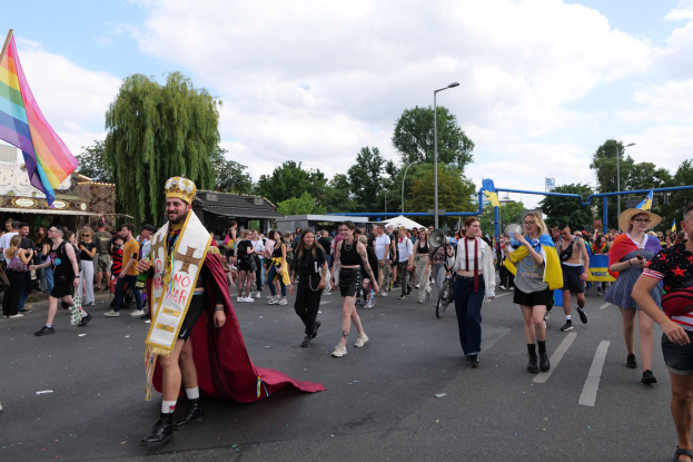 Eine Gruppe von Menschen bei der Christopher Street Day Parade 2018 mit einer Regenbogenflagge und Musikinstrumenten.