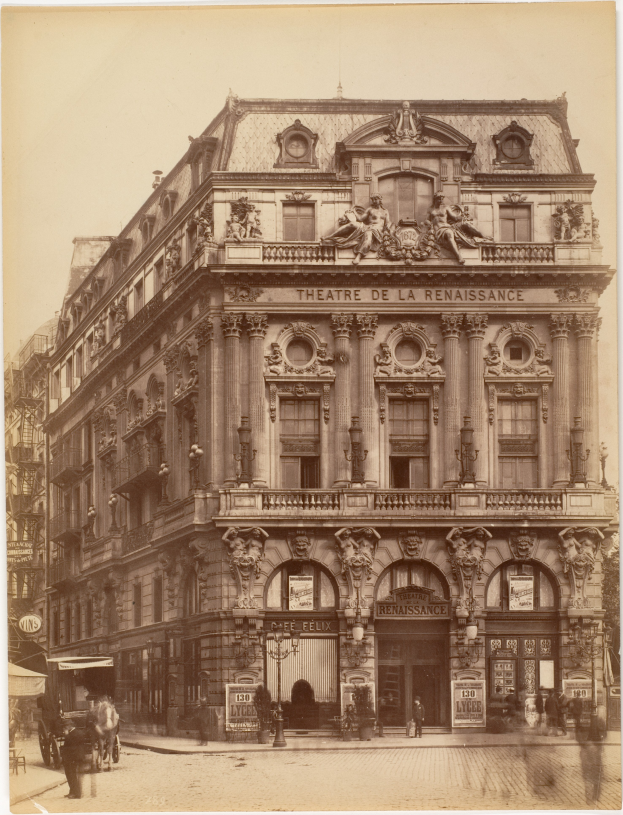 Ein altes Foto des Theatre de la Renaissance in Paris, Frankreich, das ein Gebäude mit Fenstern, Säulen, Bögen und Skulpturen an der Fassade zeigt, mit einigen Menschen und Fahrzeugen auf der Straße davor und dem Himmel im Hintergrund.