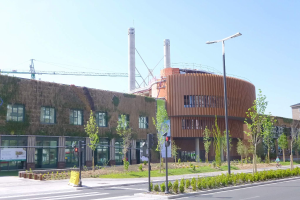 Großes grünoberes Battersea-Kraftwerk in London umgeben von Grünflächen und städtischer Infrastruktur mit Fahrzeugen und Radfahrern auf der Straße.