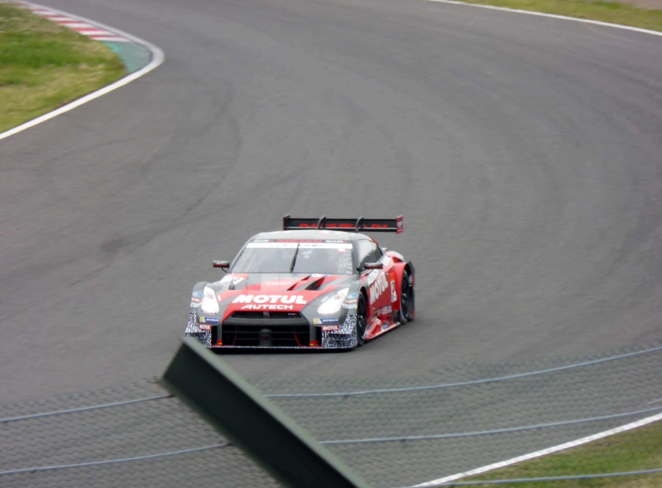 Ein Nissan GT-R Nismo GT3 Rennauto auf der Nürburgring 24 Stunden Strecke, mit grünem Gras auf beiden Seiten der Strecke.