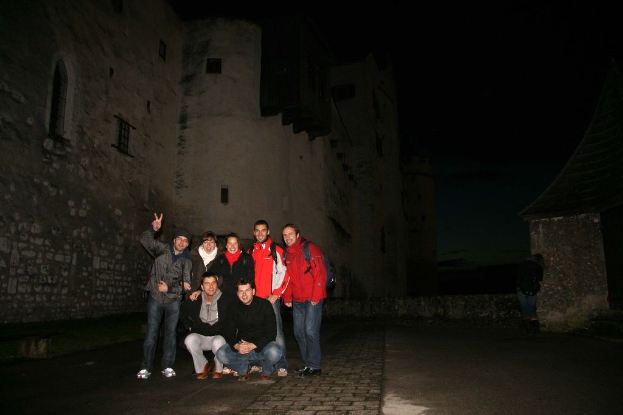 Menschen in der Mitte eines Bildes mit einem Schloss im Hintergrund bei Nacht.