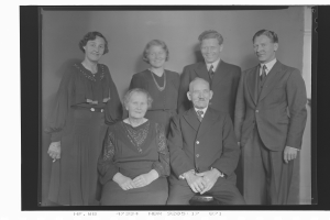 Ein Schwarz-Weiß-Foto von sechs Menschen, vier stehen und zwei sitzen, alle tragen Anzüge.