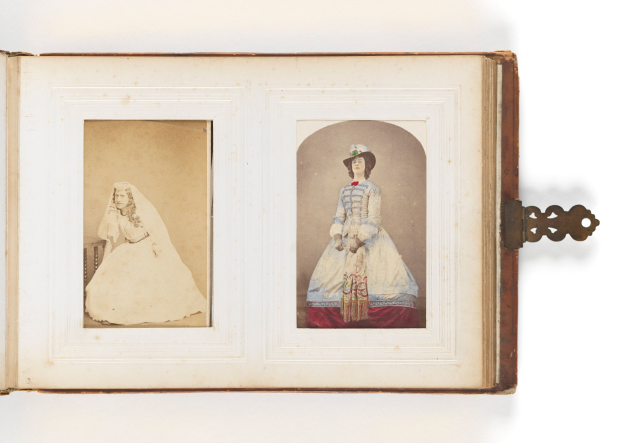 Ein altes Buch mit einer Illustration einer Braut in einem weißen Kleid mit Schleier und Tiara und eines Bräutigams in einem Anzug, der einen Strauß hält, beide strahlend und glücklich aussehend.