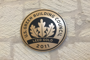Das Logo des U.S. Green Building Council auf einem Gebäude, das ein grüner Schild mit weißer Umrandung und fettem schwarzem Text zeigt, umgeben von einem Lorbeerkranz.