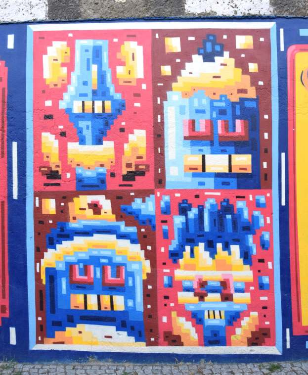 Ein leuchtendes, farbenfrohes Wandgemälde an einem Gebäude in Berlin, Deutschland, mit verschiedenen Formen und Farben.