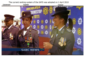 Gruppe von Menschen in Uniformen und Hüten, die vor einer Banner mit dem Text "Das aktuelle Ranglistensystem der SAP wurde am 1. April 2010 übernommen" stehen.