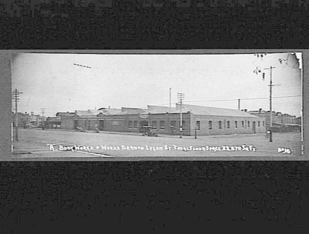 Ein Schwarz-Weiß-Foto einer Straße in Bergen, Oregon, mit Gebäuden, Strommästen, Autos und dem Text "Book House and Works" unten.