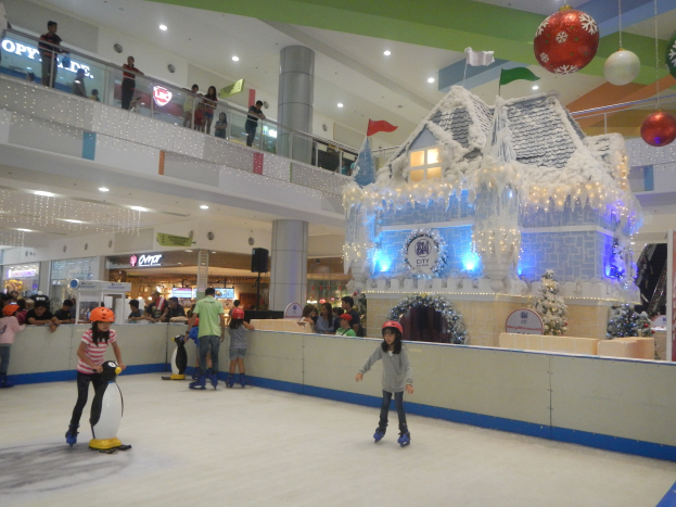 Menschen, die auf einer Indoor-Eisbahn in einem Einkaufszentrum mit festlicher Beleuchtung und Strukturen Schlittschuh laufen