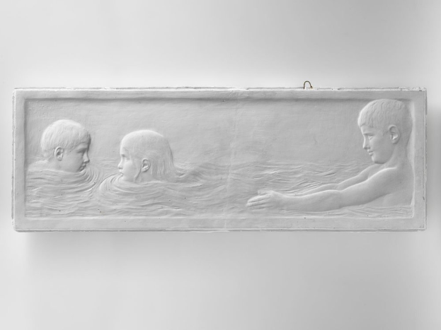 Drei Kinder schwimmen im Wasser, mit einer Wand im Hintergrund, dargestellt auf einem Schwarz-Weiß-Foto.