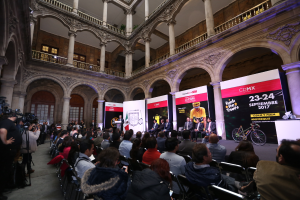 Eine Gruppe von Menschen an einem Tisch mit einem Podium und einem Mikrofon vor einer Menge, Kameras und Bannern während einer Pressekonferenz für das CDMX 2017-Event.