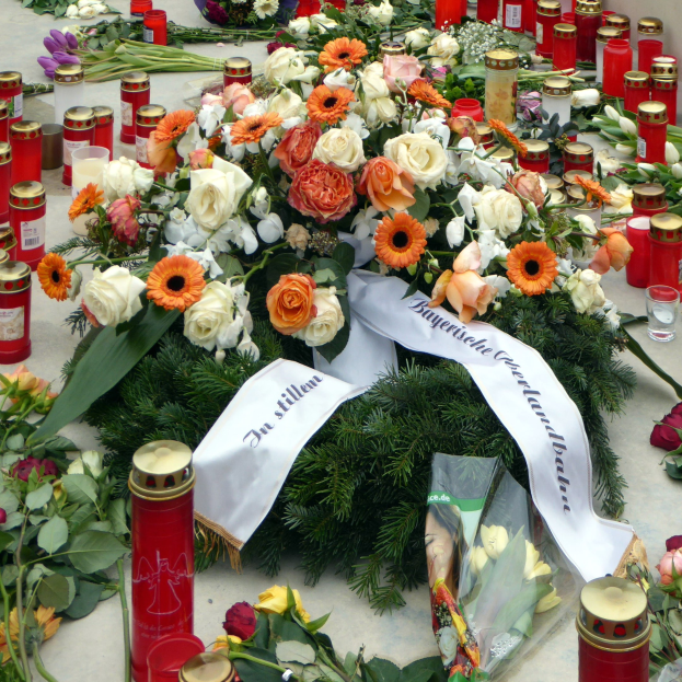 Gedenkstätte in Berlin mit Blumen und Kerzen vor einer Wand
