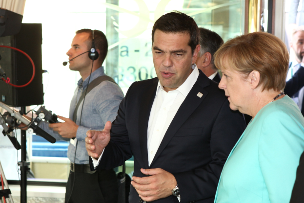 Zwei deutsche Bundeskanzler, Angela Merkel und Joachim Gauck, stehen vor einer Glaswand mit einem Vorhang dahinter, jeweils in Anzügen und mit Mikrofonen während eines Gesprächs.