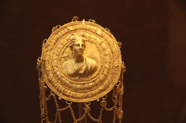 Goldene Medaille mit einer Frauengestalt auf dunklem Hintergrund, mit aufwendigen Details.