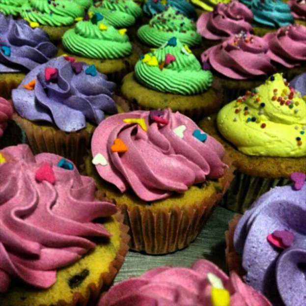 Verschiedene Cupcakes mit unterschiedlichen Toppings auf einer Fläche arrangiert.