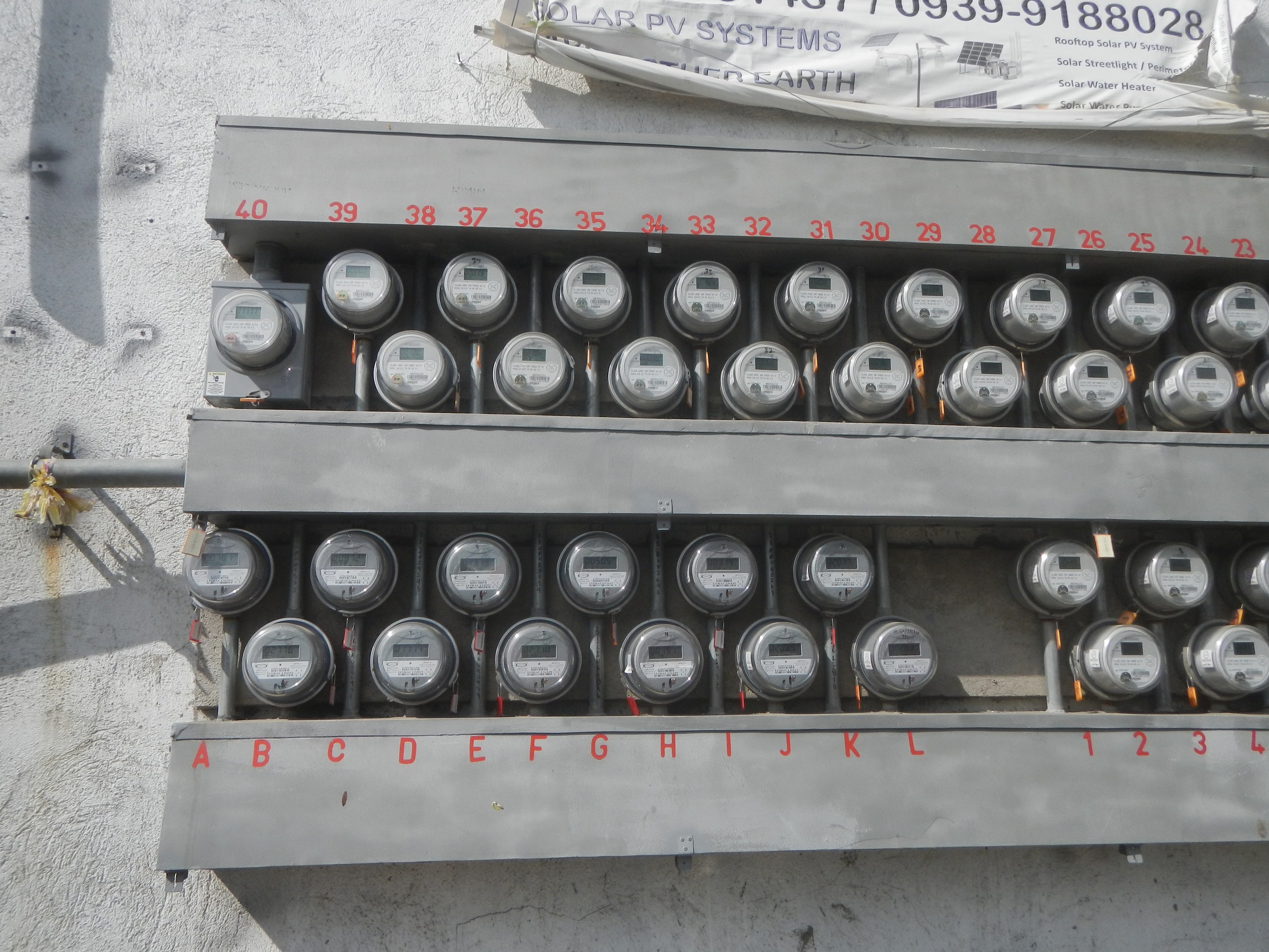 Nahaufnahme eines Elektrizitätszählers, der an der Seite eines Gebäudes montiert ist und ein Banner mit Text oben zeigt.