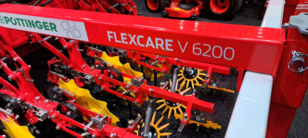 Ein roter und gelber Traktor mit der Aufschrift "Flexcare V 6200" war unter anderen Fahrzeugen zu sehen.