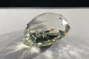 Ein elegantes gelbes Diamant funkelt auf einem schwarzen Hintergrund und reflektiert das Licht von seiner Oberfläche.