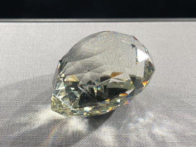 Ein elegantes gelbes Diamant funkelt auf einem schwarzen Hintergrund und reflektiert das Licht von seiner Oberfläche.