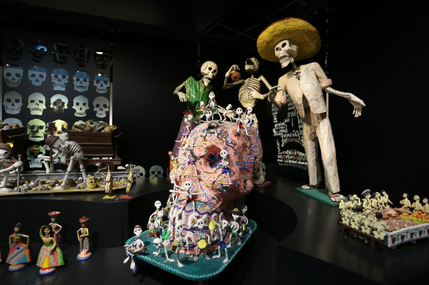 Tag der Toten Ausstellung im Museum of Fine Arts in San Francisco mit Spielzeugen, Skeletten und Objekten auf Tischen in einer dunklen, mysteriösen Atmosphäre.