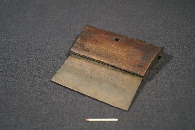 Kleiner hölzerner Streichholzschachtel mit offenem Deckel auf einer schwarzen Oberfläche, enthaltend eine Zigarette, die daneben liegt.