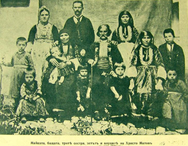 Schwarz-weiß-Foto einer Familie, die vor einer Vorhangwand posiert, beschriftet mit 'Russische Familie in den frühen 1900er Jahren'.