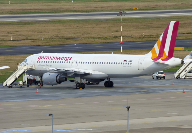 Germanwings Airbus A320-200 auf dem Frankfurt Airport mit Boden Service Fahrzeugen, Verkehrskegeln, Versorgungsmasten und Grasfläche im Hintergrund.