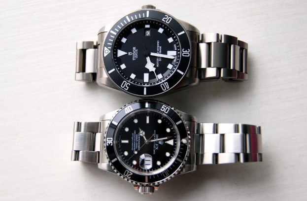 Zwei Armbanduhren sind nebeneinander auf einer flachen Oberfläche angeordnet.