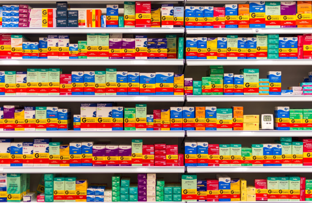 Ein Apothekeregal mit verschiedenen Medikamenten und medizinischen Versorgungsgüttern, die ordentlich auf Regalen angeordnet sind.