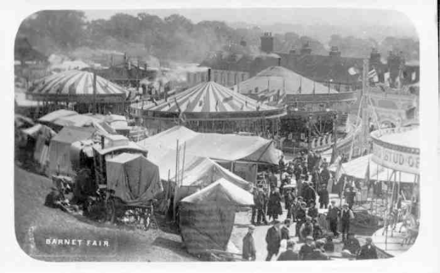 Ein altes Schwarz-Weiß-Foto vom Barnet Fair in London, England, mit Zelten, Menschen, Karren, Pfählen, Bäumen und Gebäuden im Hintergrund.